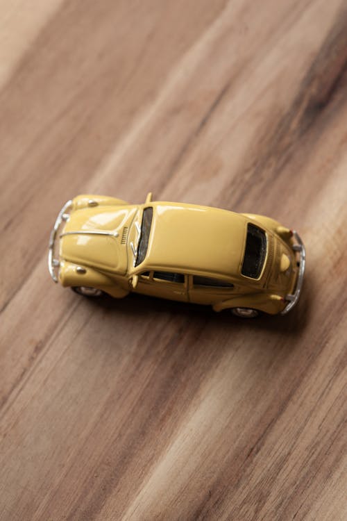 Fotos de stock gratuitas de coche amarillo, flatlay, fondo de grano de madera