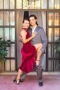 Man in Gray Suit Jacket Hugging Woman in Red Dress