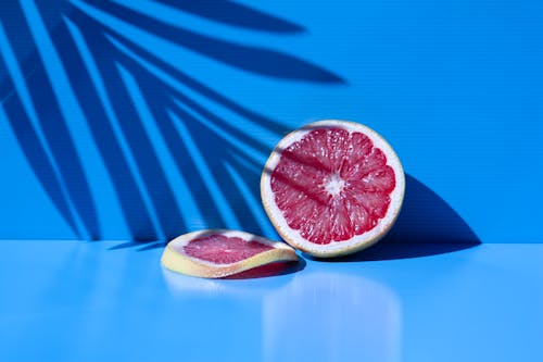 Free A Sliced of Delicious Grapefruit on Blue Background Stock Photo