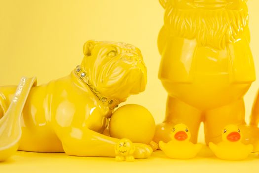A striking composition featuring a yellow bulldog figurine and rubber ducks against a vibrant yellow backdrop.