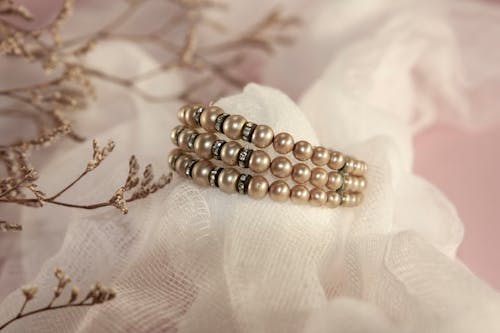 A Close-up Shot of a Pearl Bracelet on White Textile
