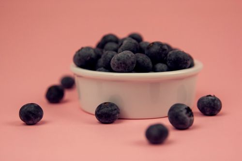 Free Close-up of fresh blueberries in a white bowl against a pink background, perfect for food-related themes. Stock Photo