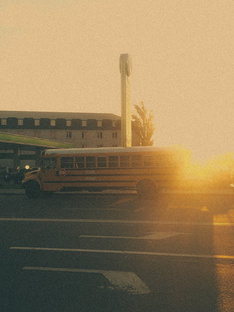 A Yellow School Bus On The Road Near A Building