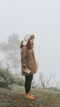 Standing woman in winter clothing with foggy Sagada backdrop.