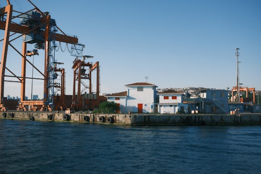 A serene view of an industrial harbor with cranes and buildings by the water.