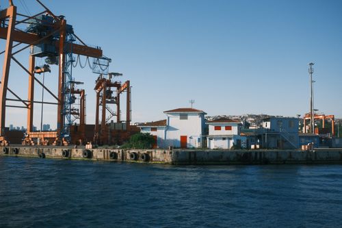 Free A serene view of an industrial harbor with cranes and buildings by the water. Stock Photo