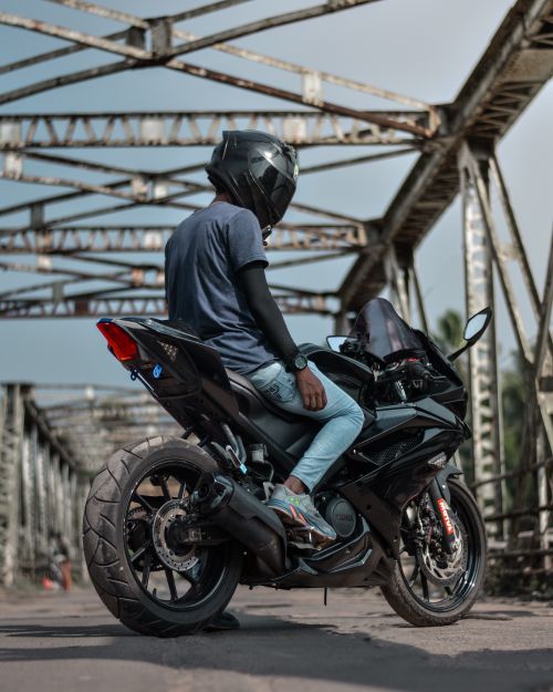 Free A motorcyclist wearing a helmet rides a motorbike on a steel bridge in Dharmadom, India. Stock Photo
