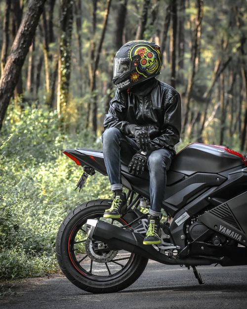 Free Biker in black leather jacket sits on a motorbike in a forest, showcasing style and safety. Stock Photo