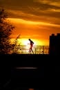 Silhouette of Woman Standing on Bridge during Sunset
