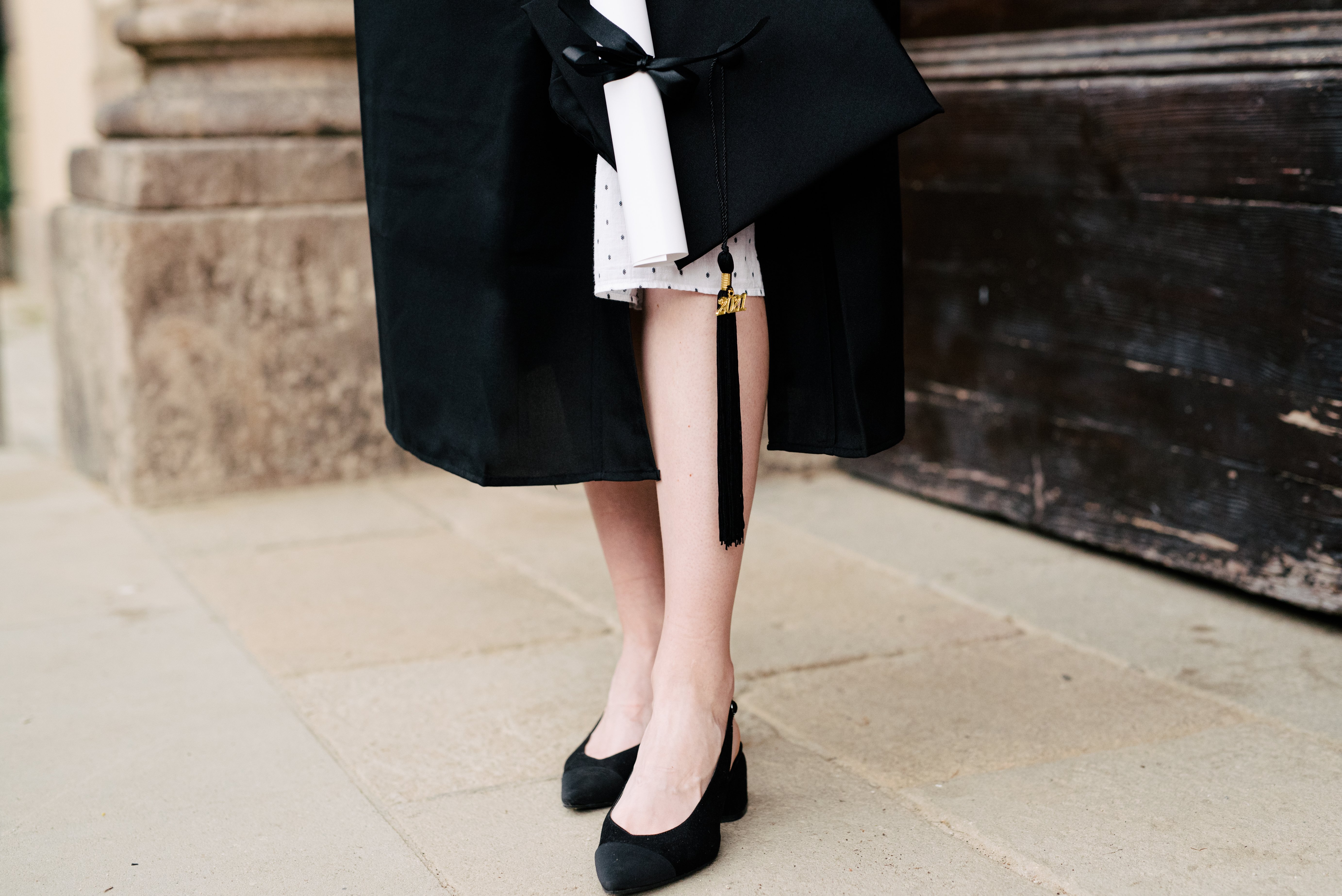 Graduate in black heels holding a diploma — the occasion that needs a heel built for the whole day