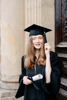 Young woman in graduation attire smiling with diploma in hand.