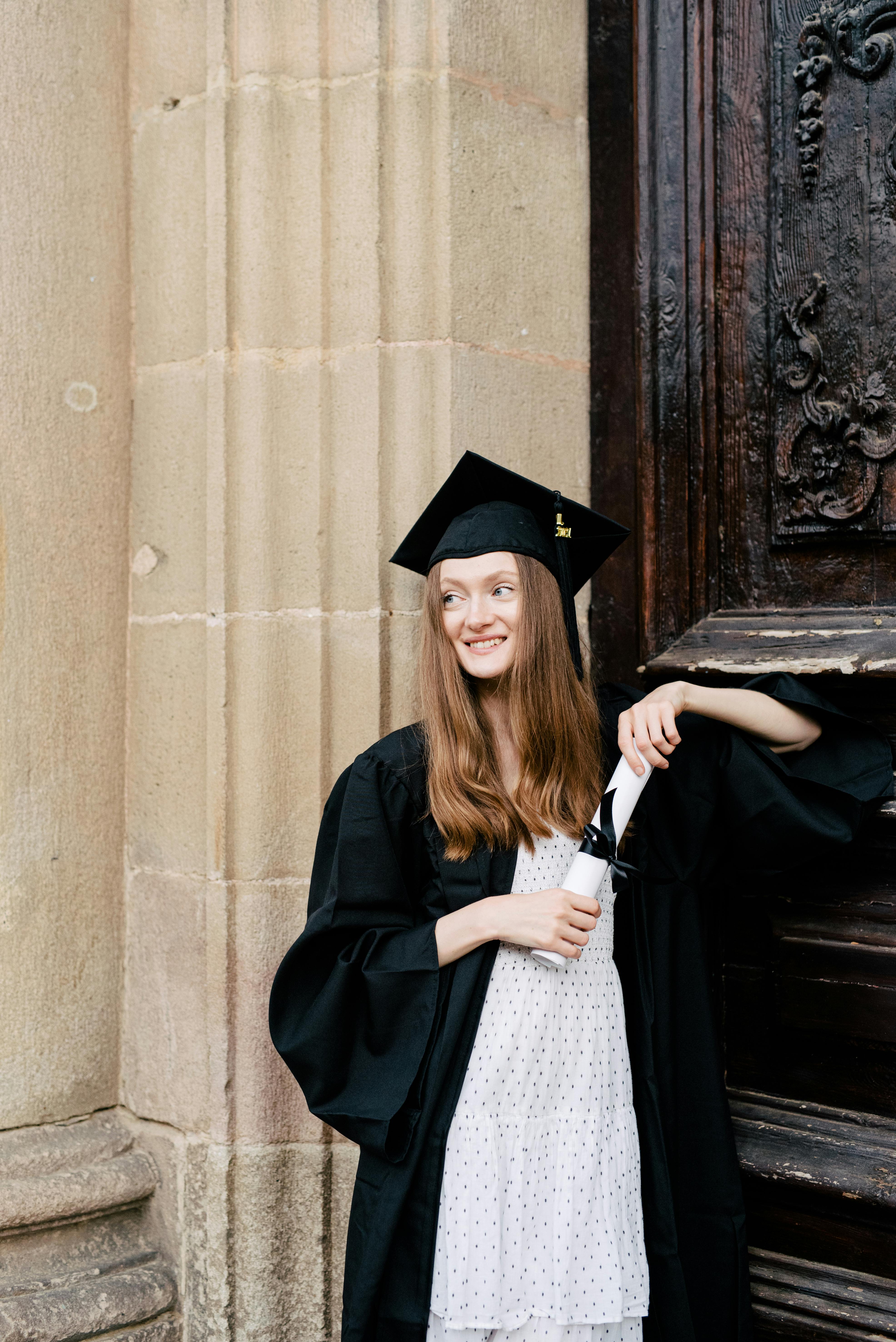Portrait of happy young female graduates in academic dress and square  academic cap holding word quotes of CONGRATS GRAD on balloon after  convocation c Stock Photo - Alamy