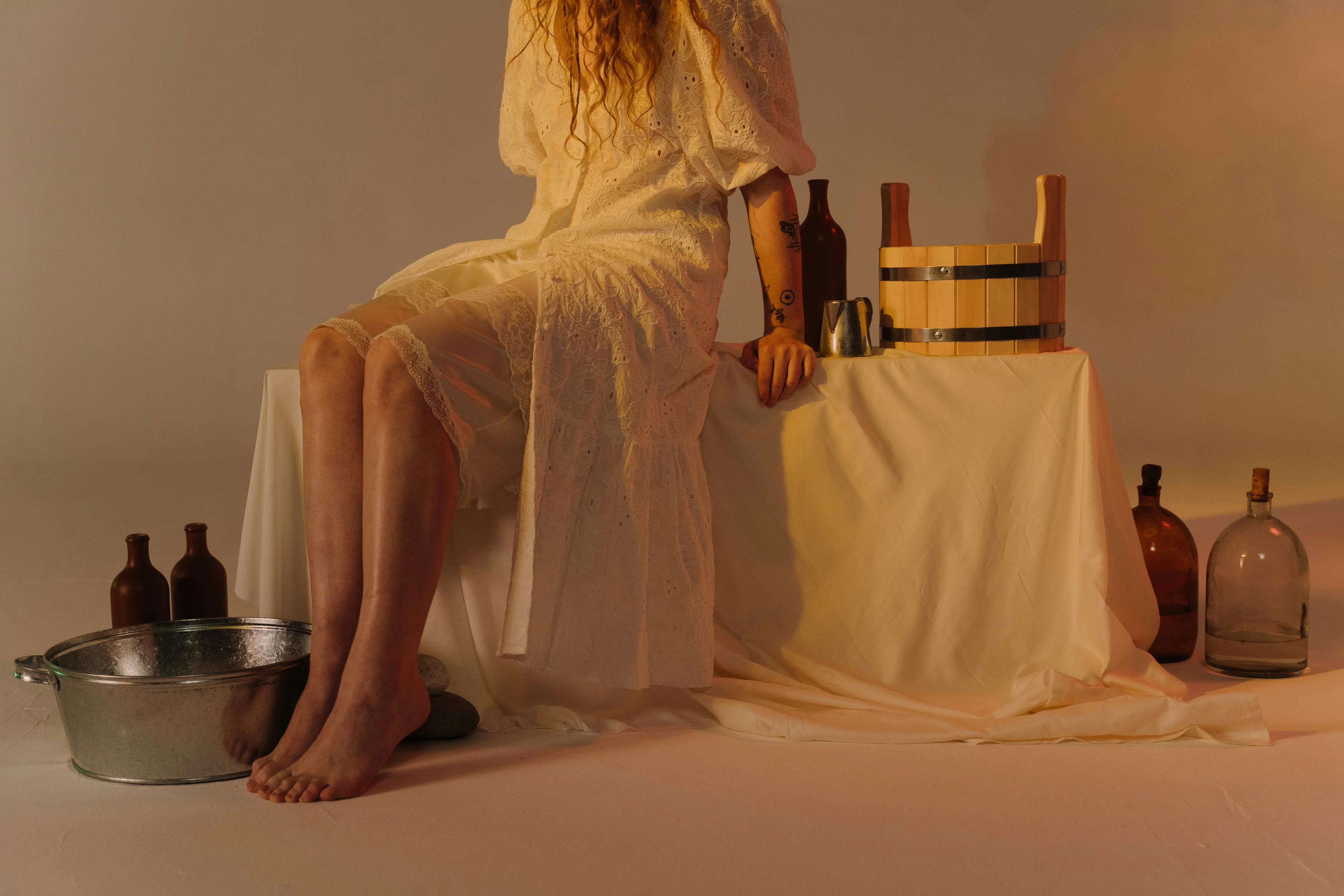 Woman in white lace dress sitting with vintage objects, creating a calm and nostalgic atmosphere.