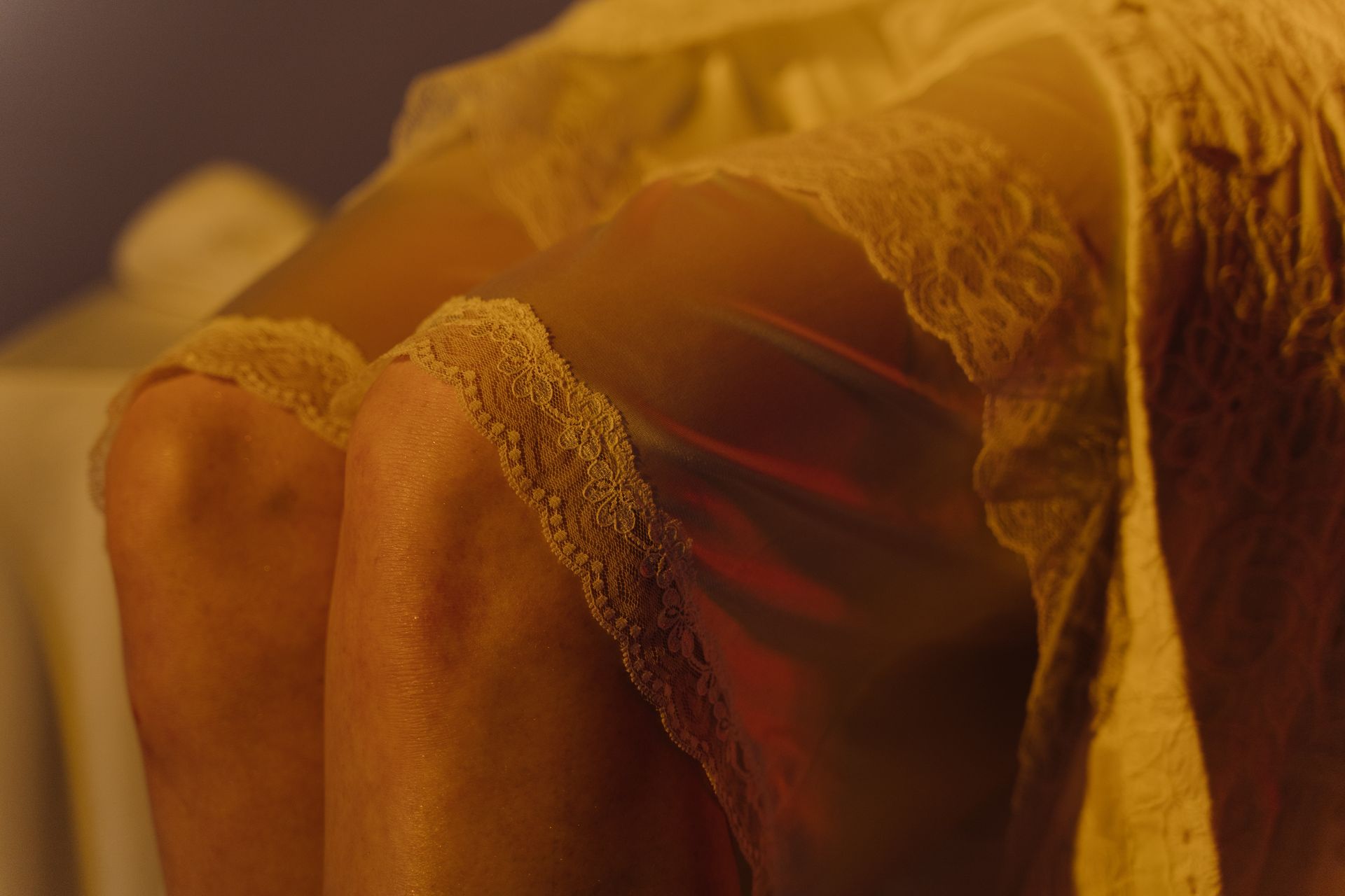 Close-up image featuring intricate lace detailing on soft silk fabric in warm lighting.