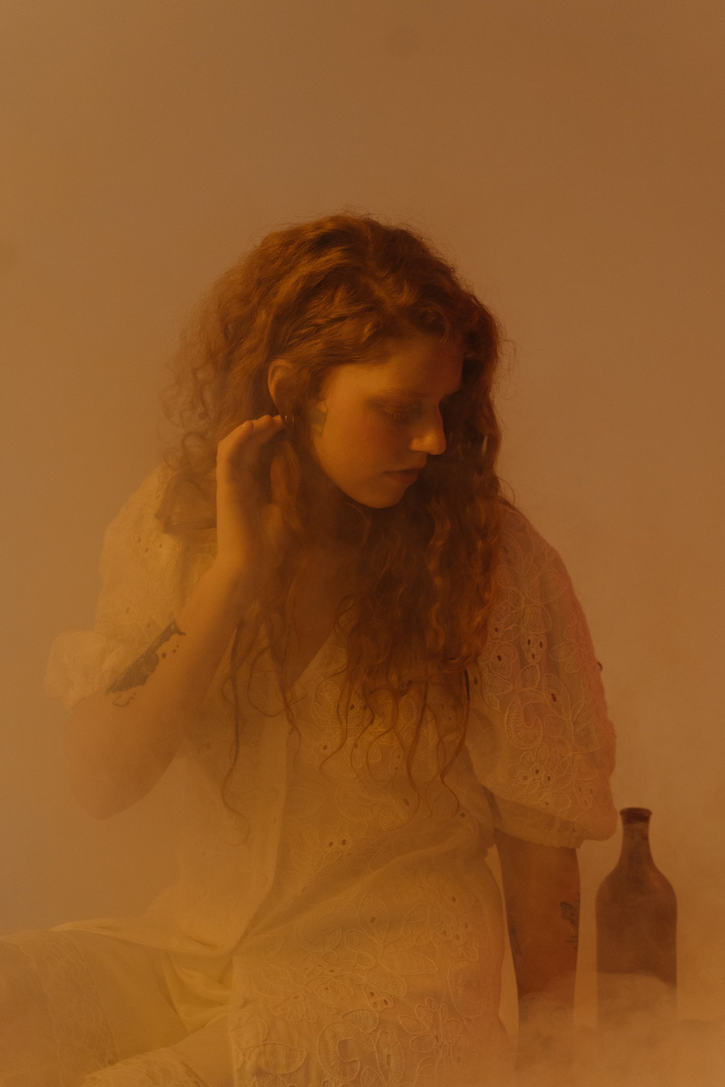 Dreamy portrait of a woman with curly hair in a misty setting, exuding a serene and introspective mood.
