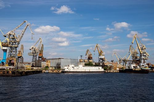 Free View of cranes and industrial harbor in Saint Petersburg, under a clear blue sky. Stock Photo