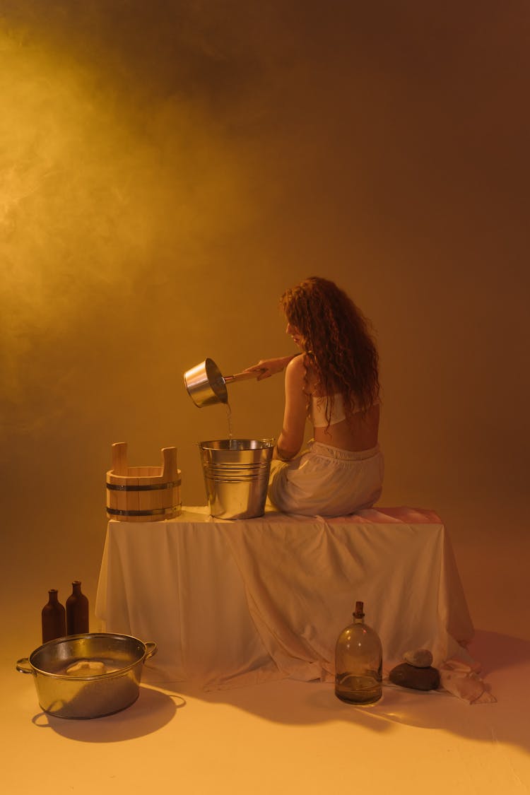 Woman Pouring Water On A Bucket