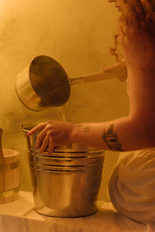 Woman Pouring Water on Stainless Steel Bucket