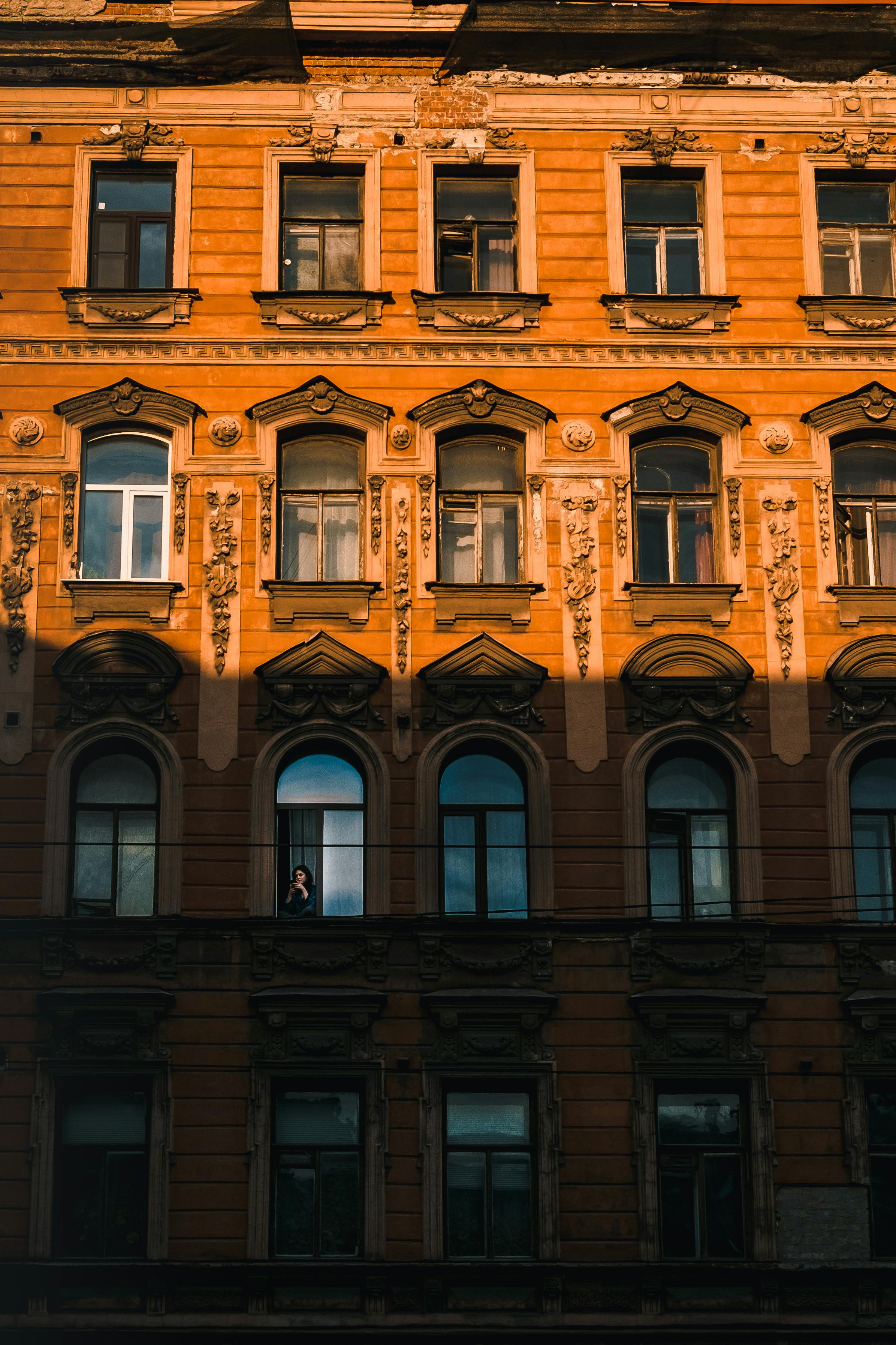 A detailed view of a historic building facade in Saint Petersburg, Russia, illuminated by the warm glow of sunset.