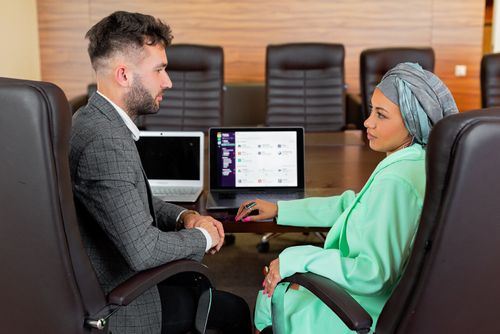 Free Professional business meeting with two diverse individuals using laptops in a modern conference room. Stock Photo