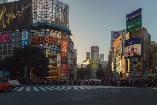 Free Experience the vibrant and dynamic atmosphere of Shibuya Crossing in Tokyo during sunset with crowds and illuminated billboards. Stock Photo