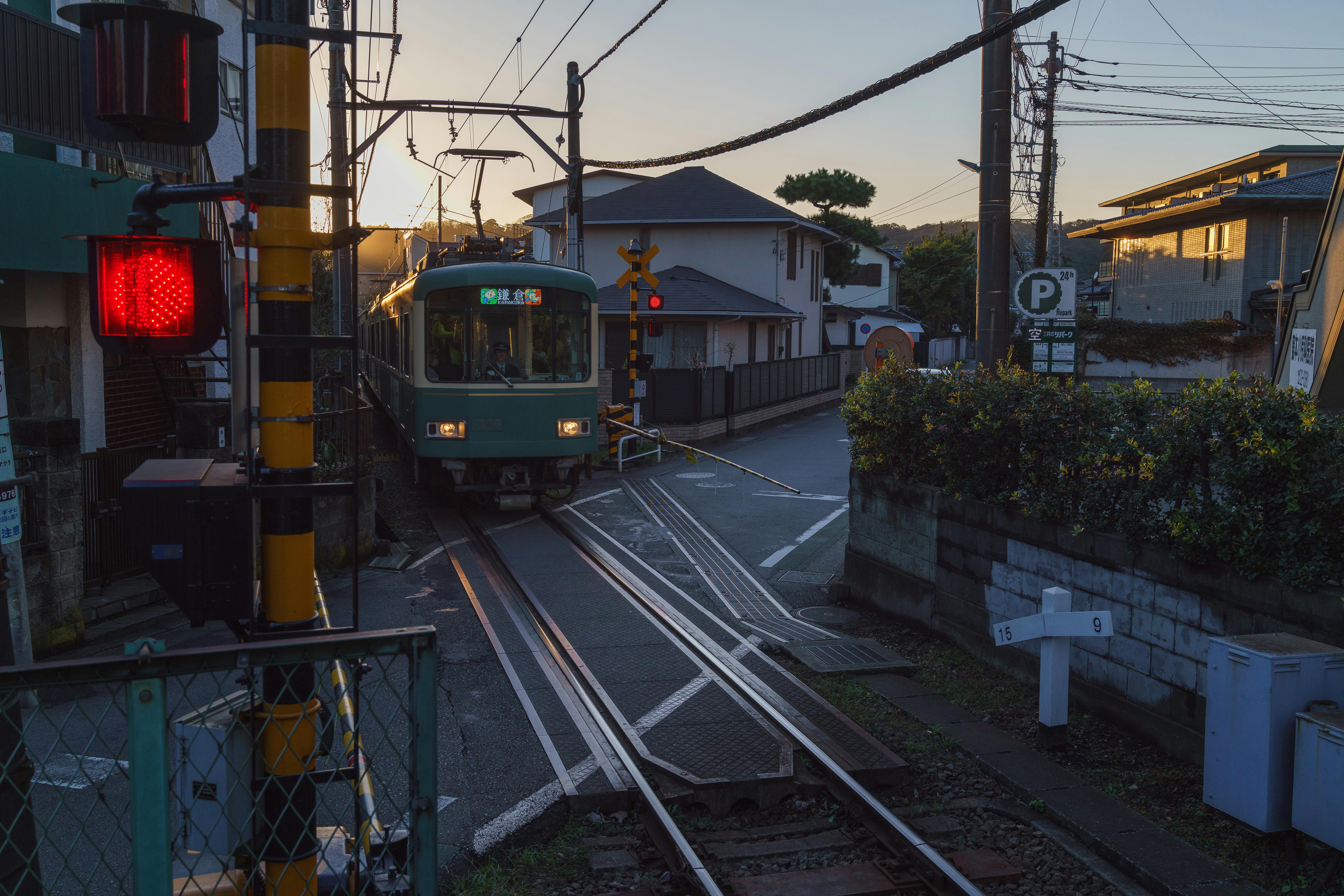 A serene street scene in Kamakura, Japan, featuring a railway crossing at dawn.