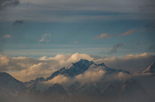Free Breathtaking view of snow-capped mountain peaks enveloped in winter mist under a cloudy sky. Stock Photo