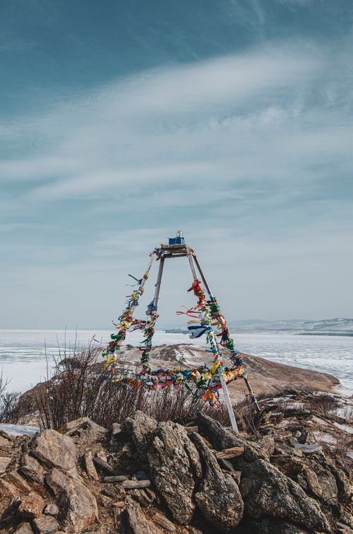 Free Vibrantly wrapped structure with ribbons on a rocky coast under a vast sky. Stock Photo