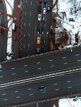 Top-down drone view of a snowy city intersection with multiple vehicles in traffic.