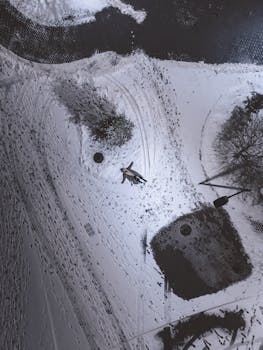 Explore a serene aerial scene of a snow-covered landscape with a person making snow angels.