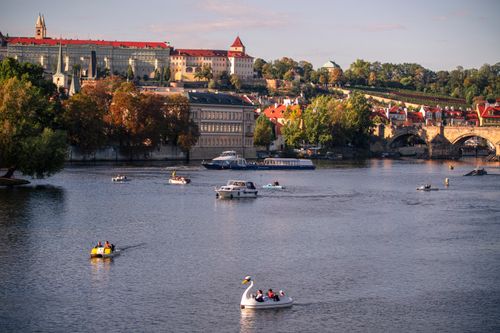 Free Picturesque view of swan boats and historic architecture on the Vltava River in Prague. Stock Photo