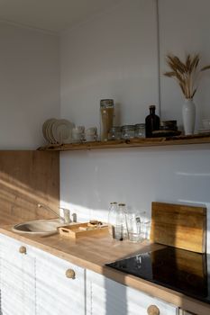 A sunlit minimalist kitchen interior with modern decor and wooden accents.