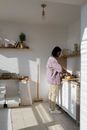 Woman in Pink Robe Standing in Front of Kitchen Sink