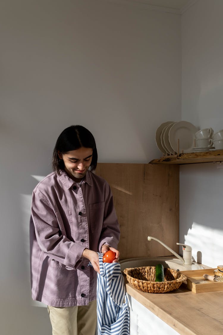 A Man In Pink Jacket Wiping The Tomato Using A Towel