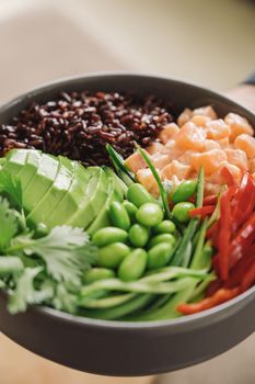 Close-up of a colorful poke bowl with salmon, avocado, and edamame, perfect for healthy eating.