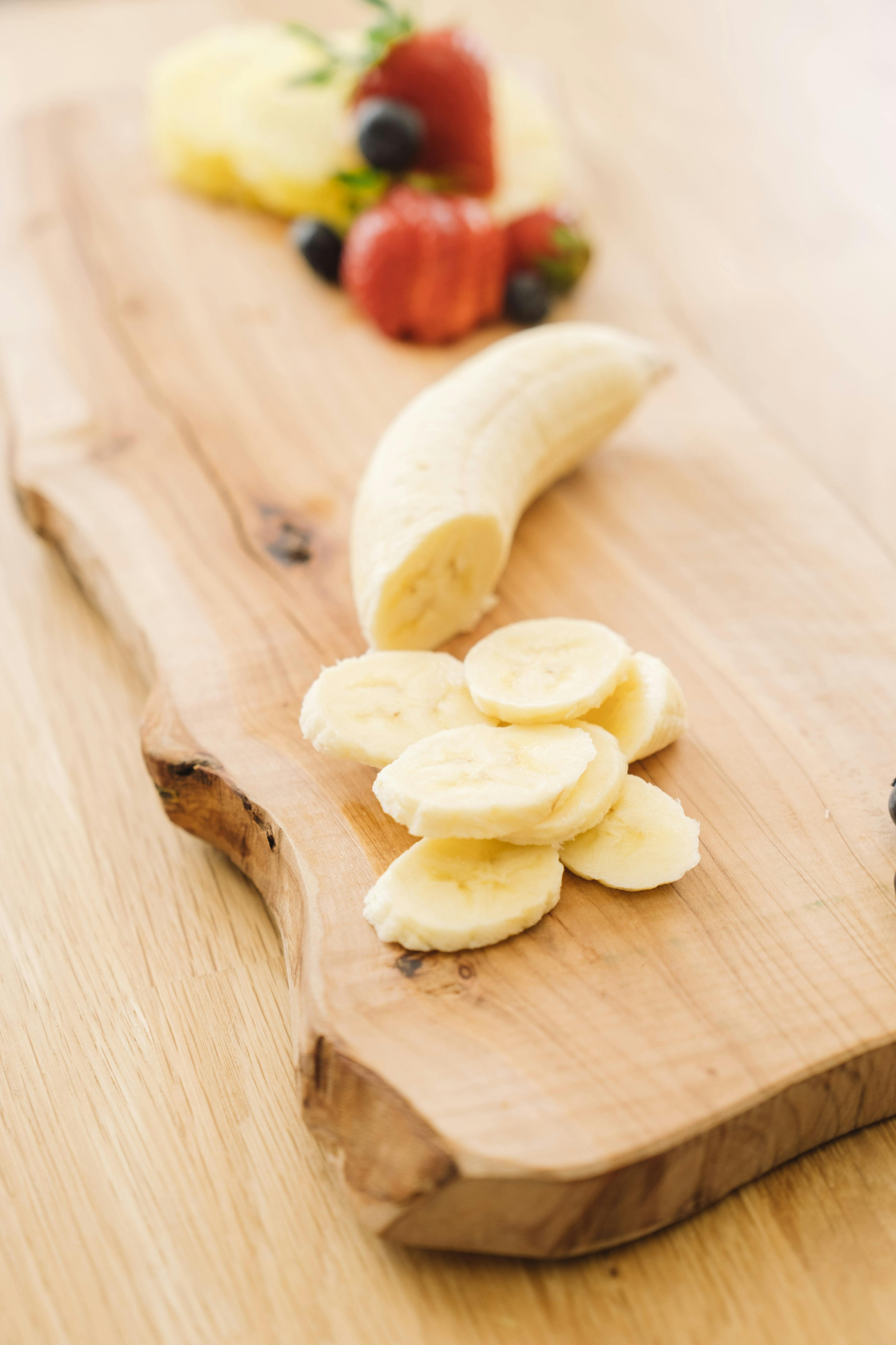 Sliced banana and fresh berries artfully arranged on a rustic cutting board for a healthy snacking concept.