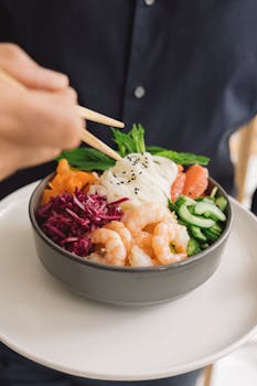 Colorful poke bowl featuring shrimp, vegetables, and rice, perfect for food enthusiasts.