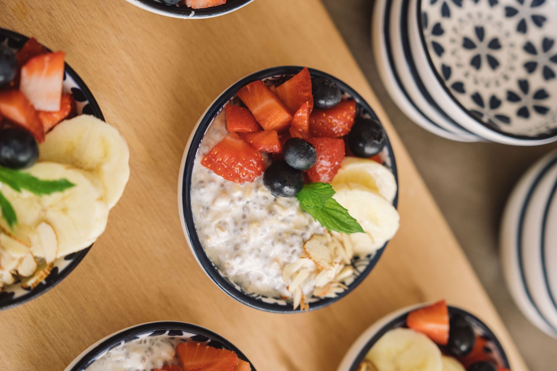 Light and Fresh Meal Prep Ideas for Summer Days Overhead view of oatmeal bowls topped with fresh fruits like bananas, strawberries, and blueberries.