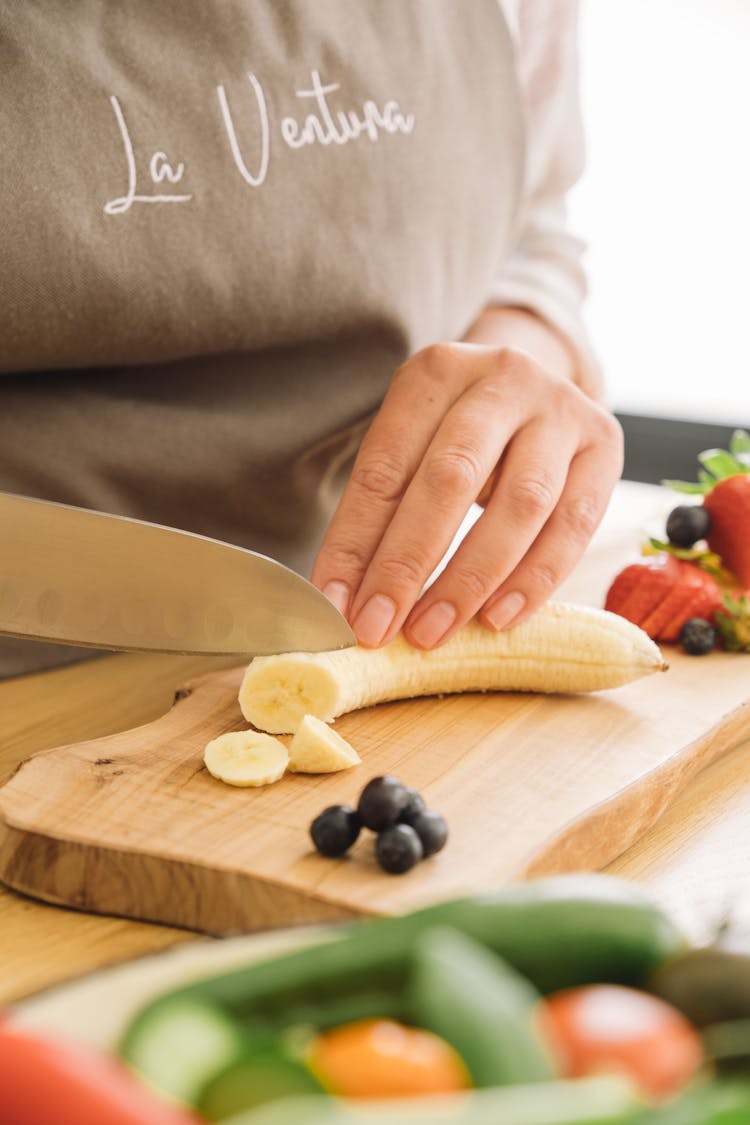 A Person Slicing A Banana