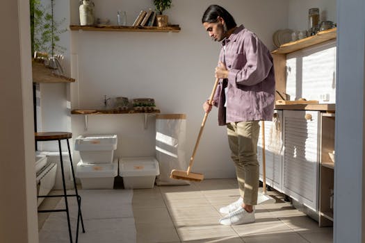 A man in casual attire cleans a stylish kitchen, emphasizing eco-friendly living.