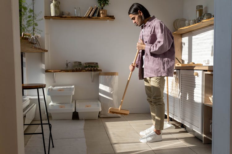 A Man Sweeping The Kitchen Floor