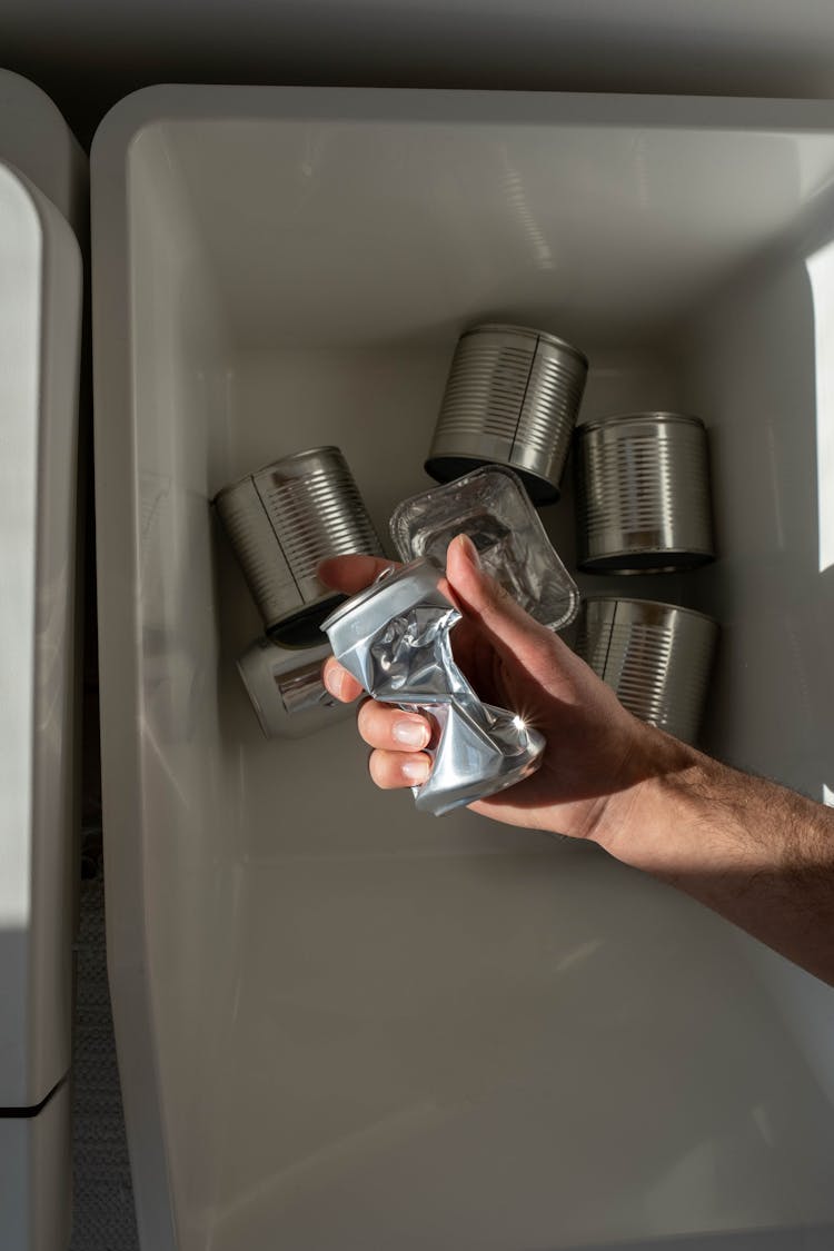 A Person Holding A Crushed Can