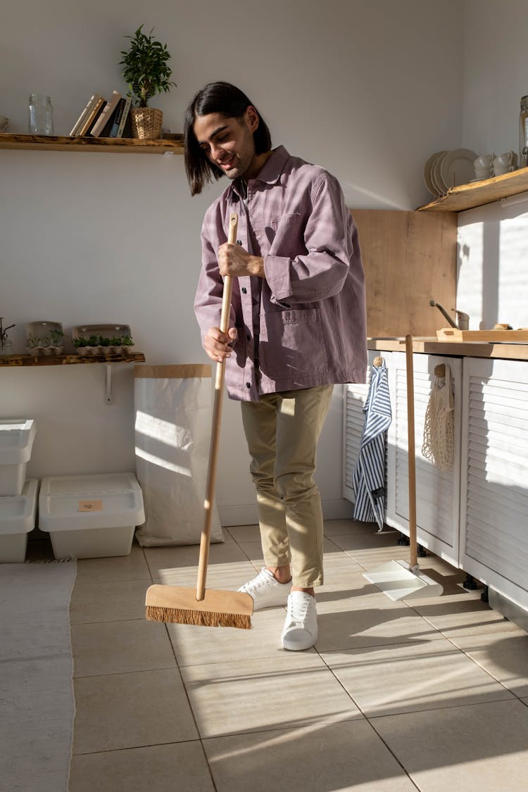 A Long Haired Man Holding A Broom