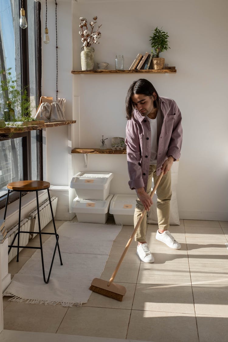 A Long-Haired Man Sweeping The Floor