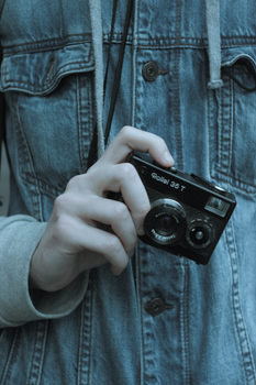 Person holding a vintage Rollei 35 T camera with a denim jacket backdrop.