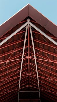 Low angle shot of a modern steel truss roof structure with a clear blue sky background.