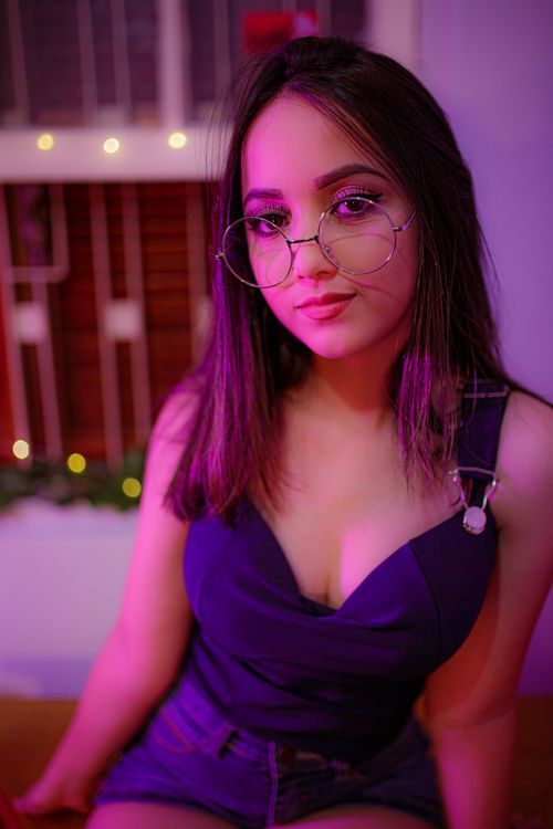 Free Portrait of a young woman wearing eyeglasses indoors with soft lighting. Stock Photo