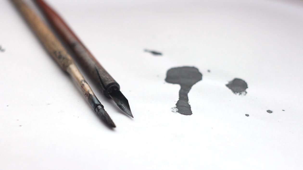 A fountain pen and ink bottles on a workspace — ink mixing setup