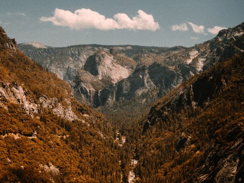 Free Serene mountain valley with rocky formations and forest under a clear sky. Stock Photo