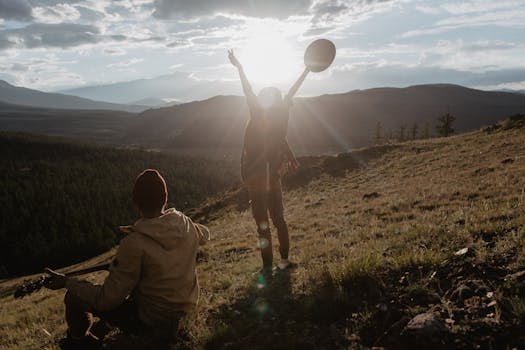Two people enjoying a musical moment on a hillside at sunset, embracing nature and freedom.